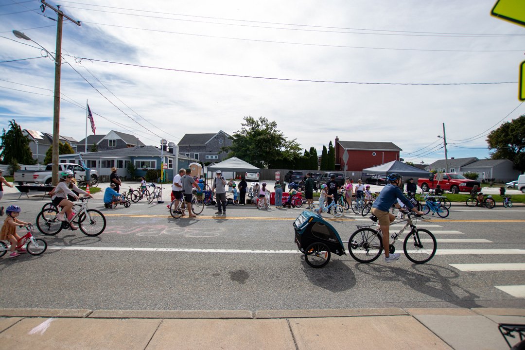A crowd of cyclists and bikes gathered on Park Avenue during the 2026 Sakonnet Coastal Bike & Stroll