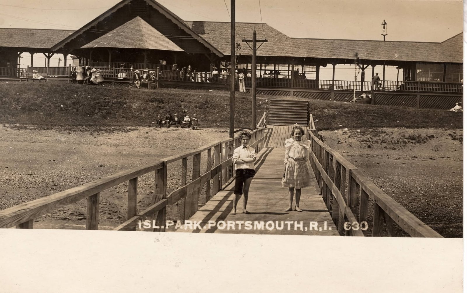 Vintage photo of children on an Island Park boardwalk with a pavilion and crowd in the background, Portsmouth, Rhode Island